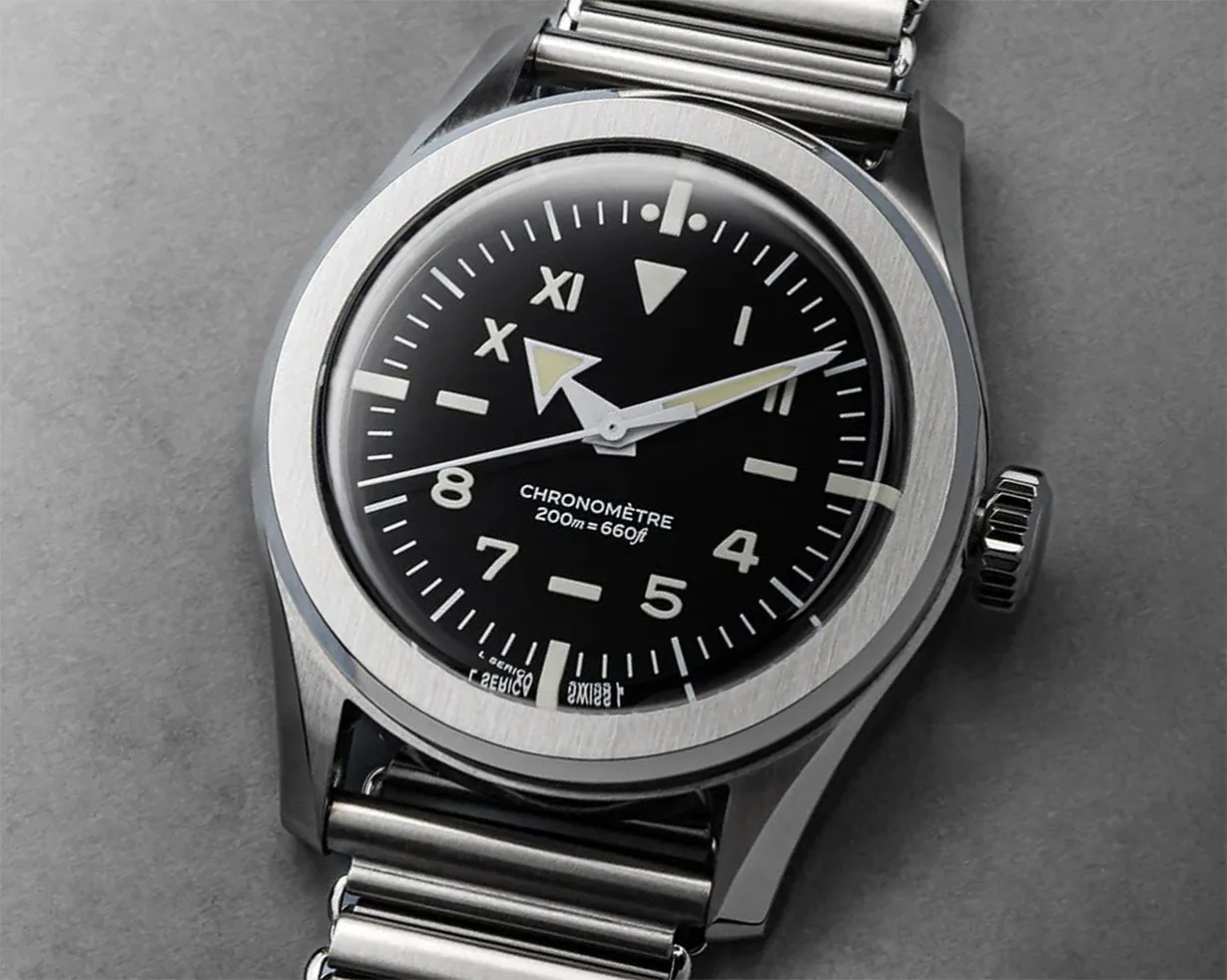 Stainless steel wristwatch with black dial, luminous hands, and mixed Roman and Arabic numerals on a metal bracelet.