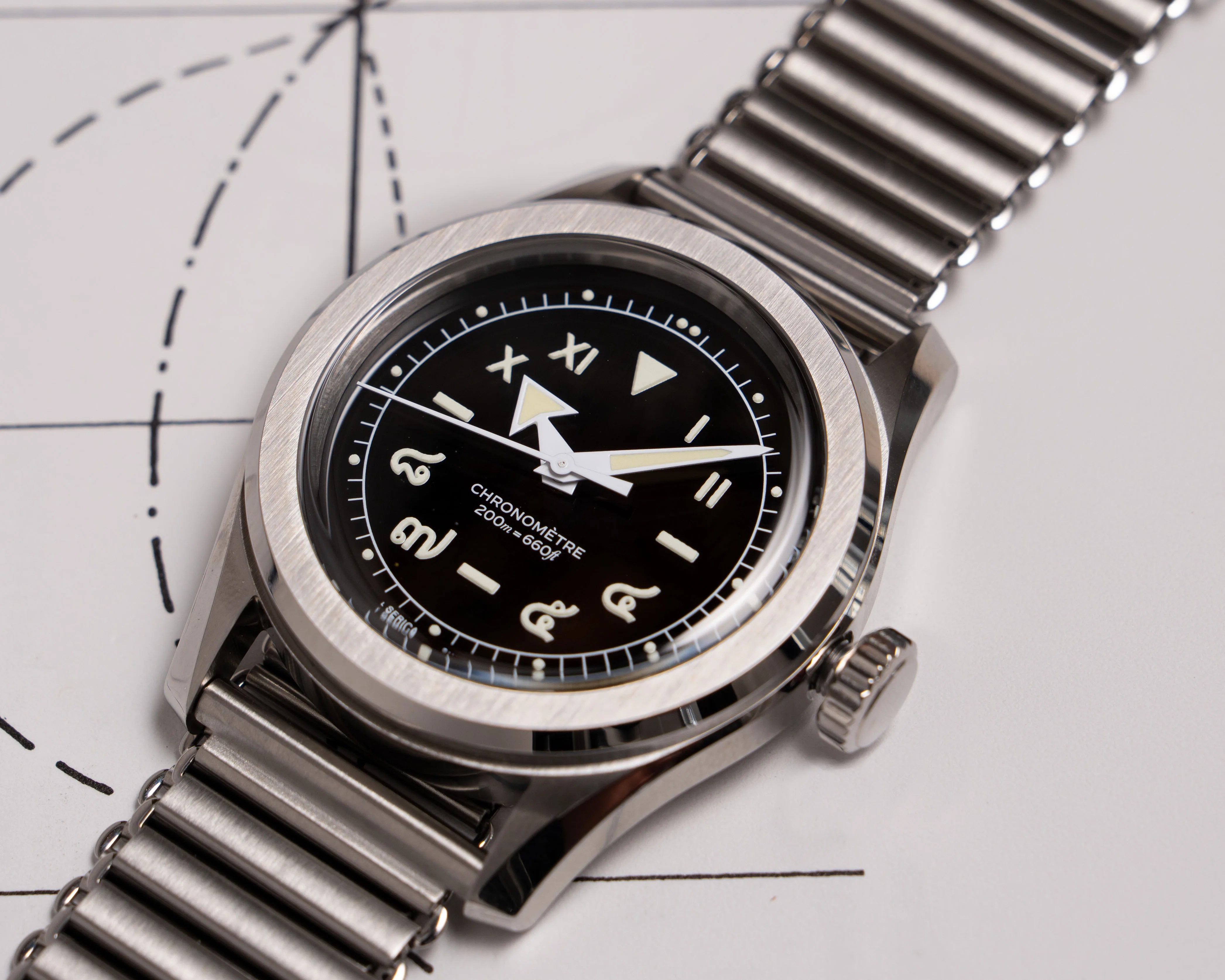 Stainless steel wristwatch with black dial featuring unique numeral markers and luminous hands on a metal bracelet.
