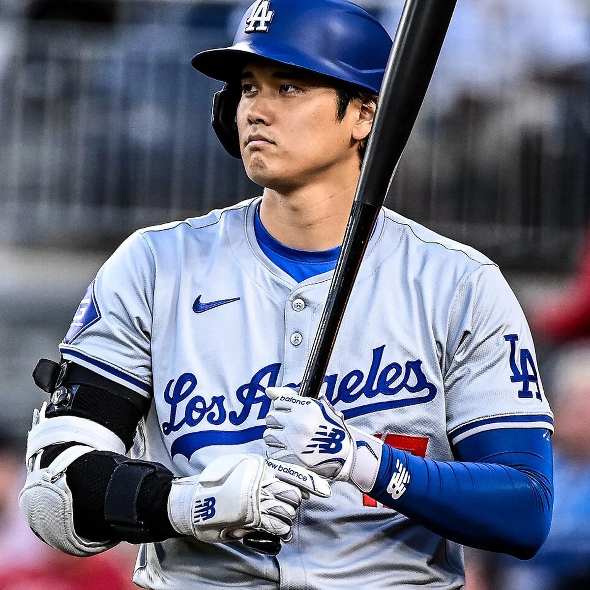Baseball player in a Los Angeles Dodgers uniform holding a bat, wearing a blue helmet and white batting gloves.