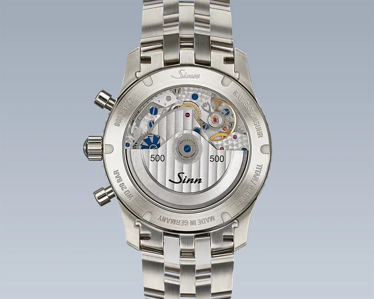 Back view of a Sinn wristwatch with a transparent case back showing the mechanical movement and a stainless steel bracelet.