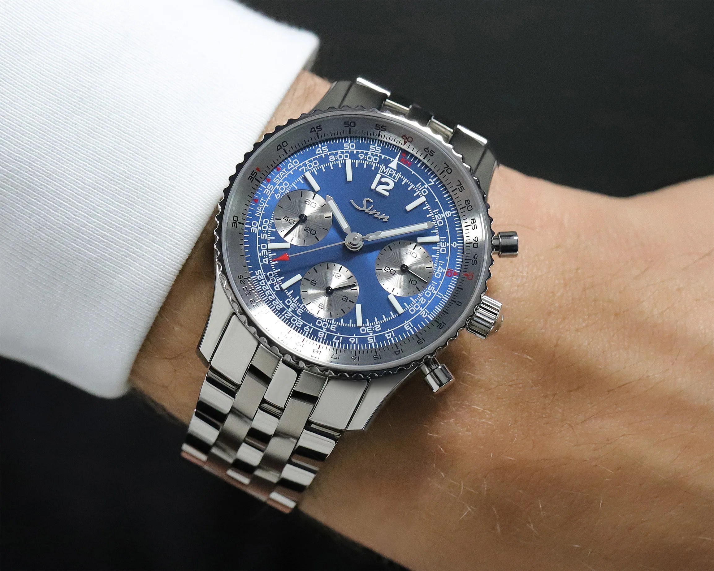 Silver Sinn chronograph wristwatch with blue dial and three subdials on a metal bracelet worn on a wrist.