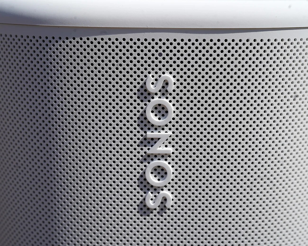 Close-up of a white Sonos speaker grille with the brand name vertically centered.