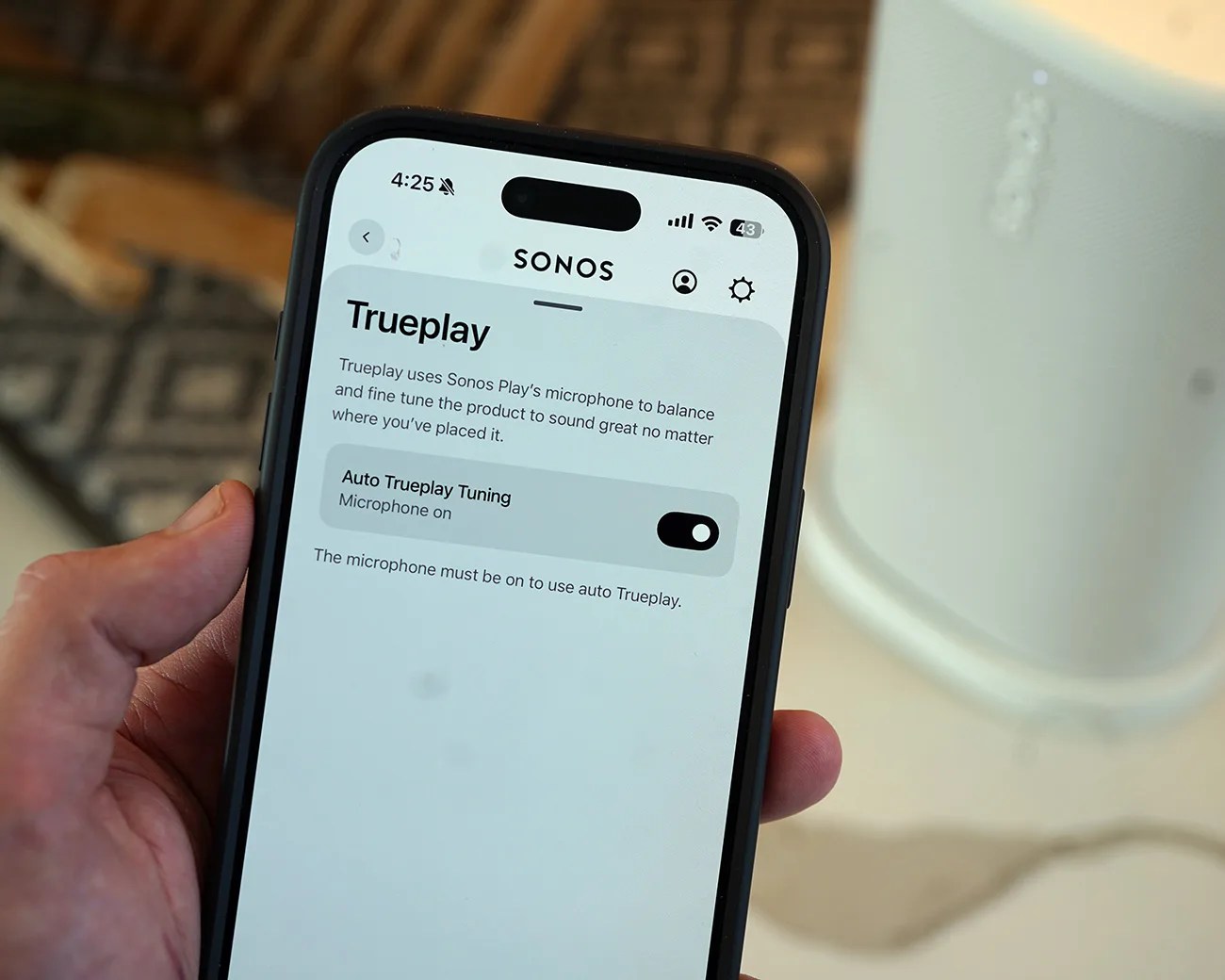 Smartphone screen showing Sonos Trueplay auto tuning feature with microphone on, held in a hand.