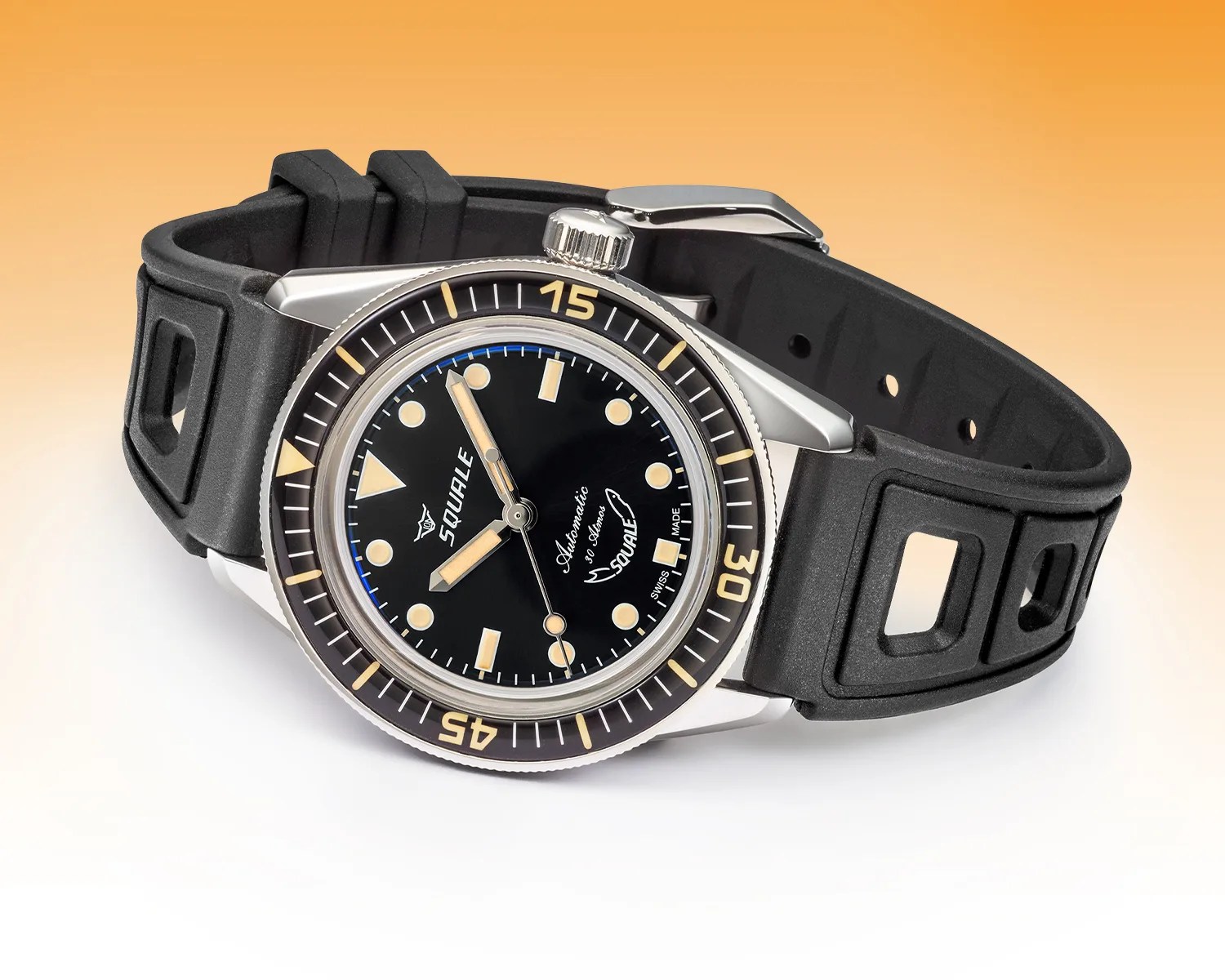 Squale dive watch with black dial, beige markers, rotating bezel, and black rubber strap on gradient background.