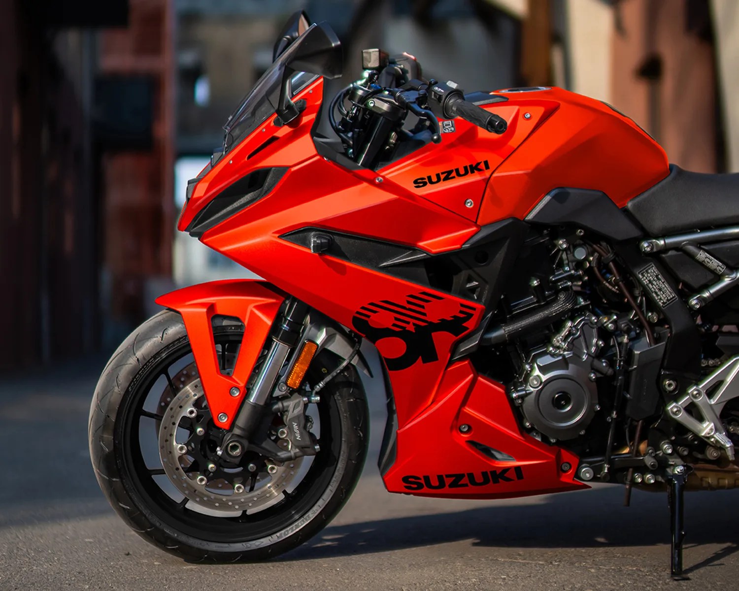 Red Suzuki sport motorcycle front and side view showing front wheel, fairing, and engine details.