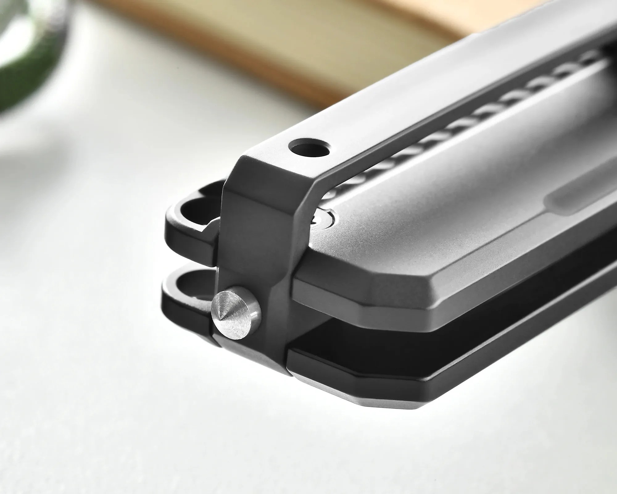Close-up of a metallic gray folding knife handle with a textured grip and a visible pivot screw.