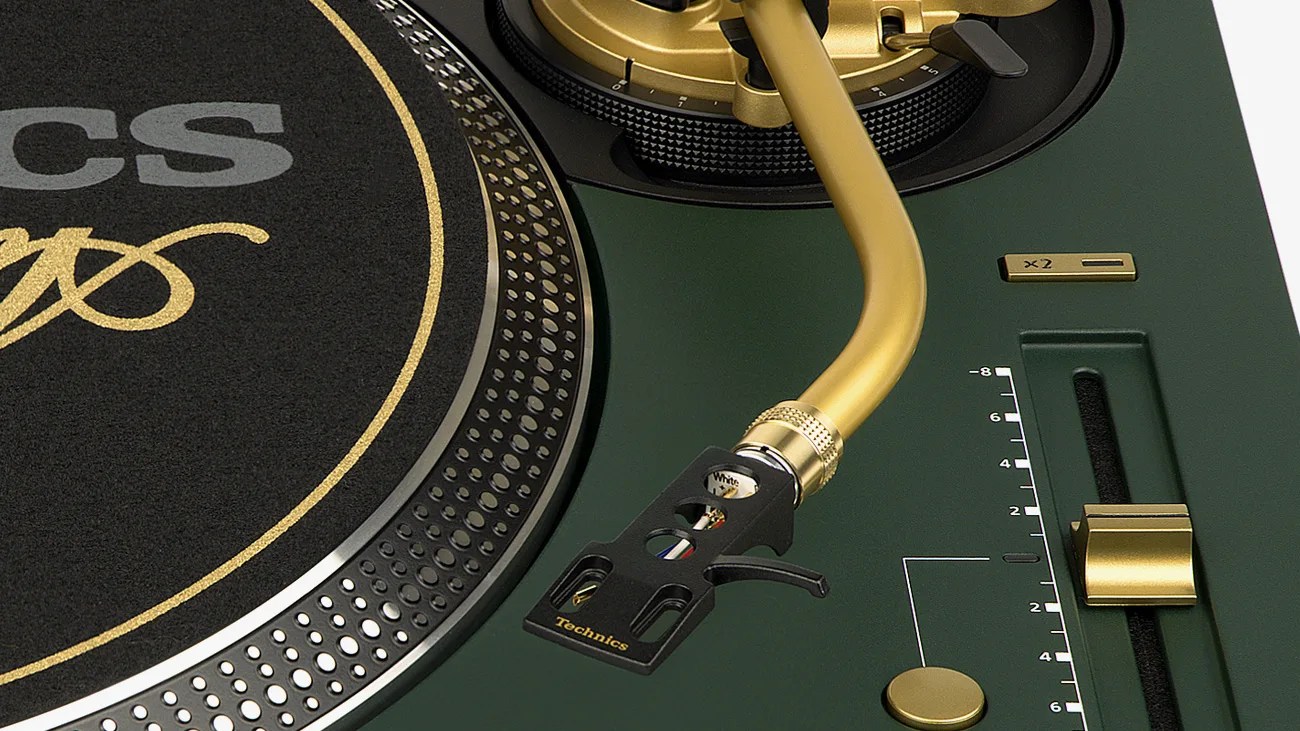 Close-up of a green Technics turntable with a gold tonearm and black cartridge.