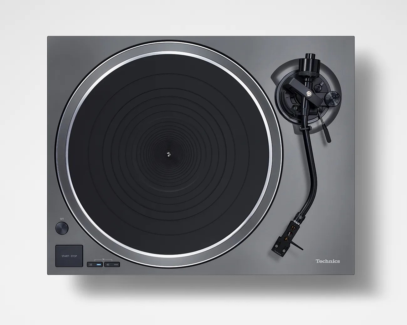 Top view of a gray Technics turntable with black tonearm and circular platter on a white surface.