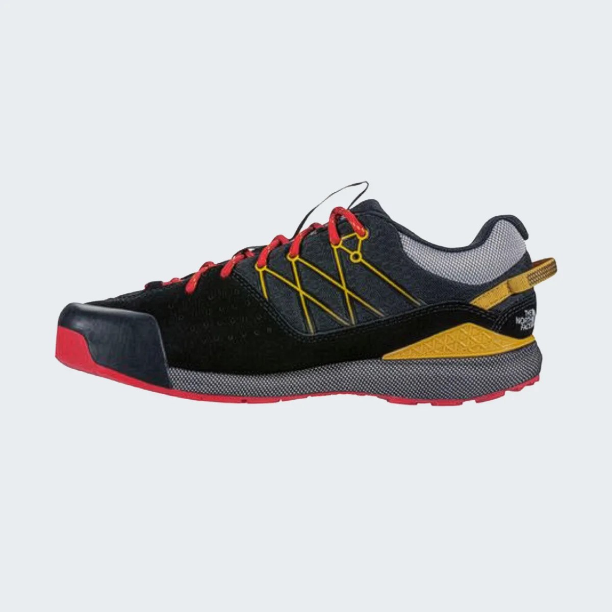Black and gray low-top sneaker with red laces, red sole, and yellow accents on a white background.