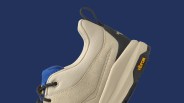 Beige and blue sneaker with black laces and Vibram sole on a dark blue background.