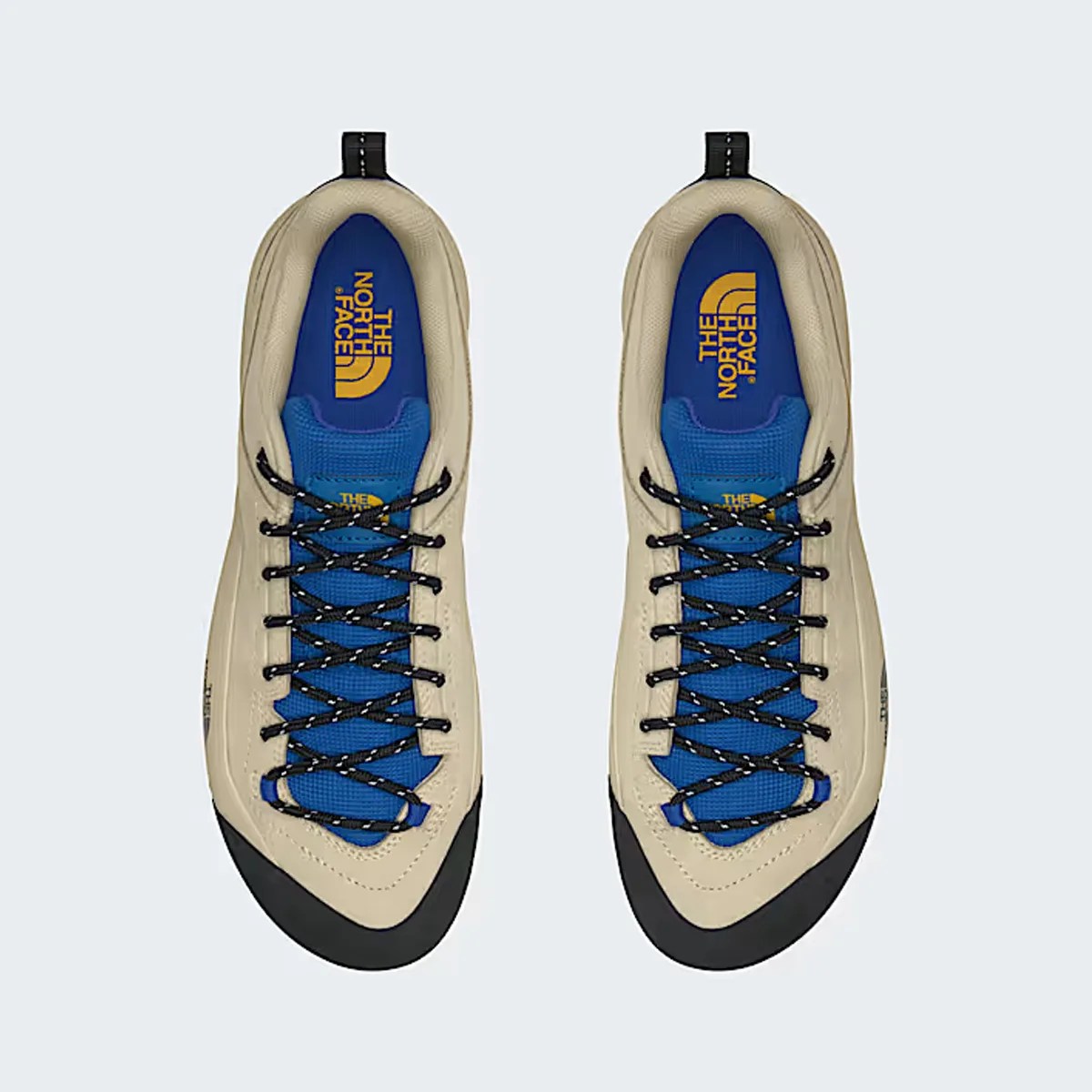 Pair of beige and blue The North Face hiking shoes with black laces and rubber toe caps, top view.