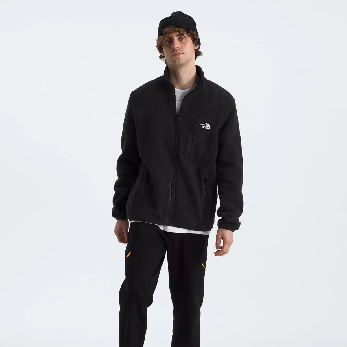 Man wearing a black fleece jacket with The North Face logo on the chest and a black beanie.