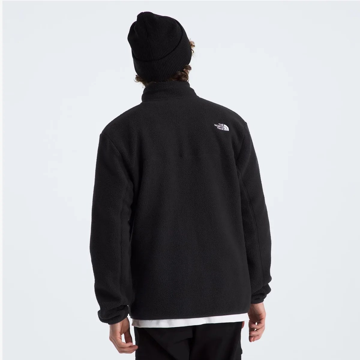Person wearing a black fleece jacket with The North Face logo on the upper back and a black beanie.