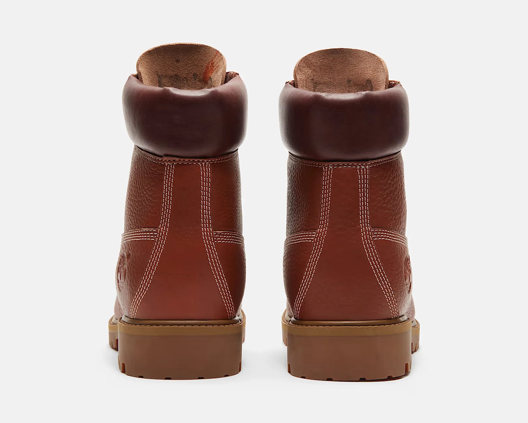 Pair of brown leather boots with padded collars and thick rubber soles shown from the back.