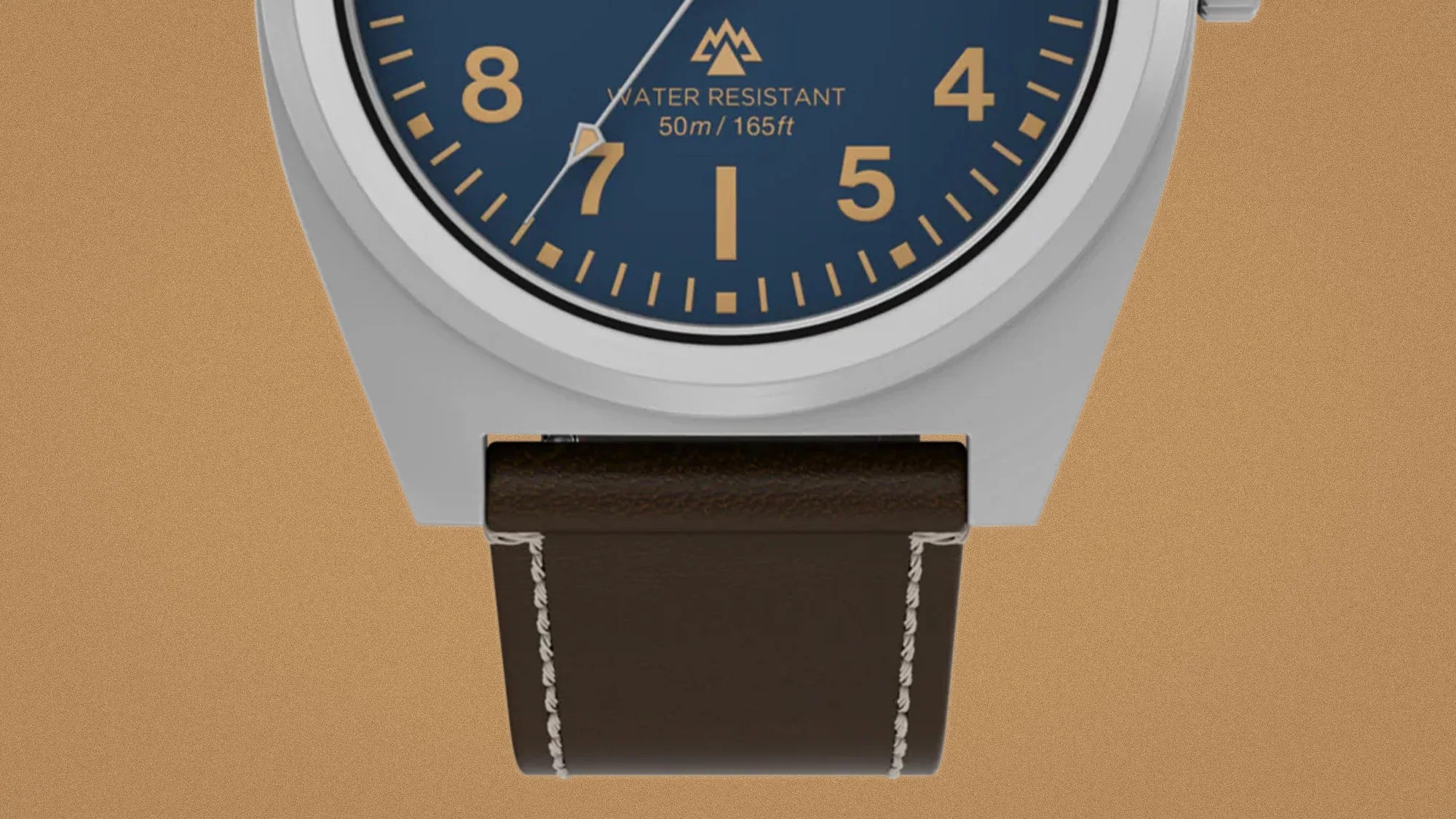 Close-up of a watch with a blue dial, gold numerals, silver case, and dark brown leather strap with white stitching.