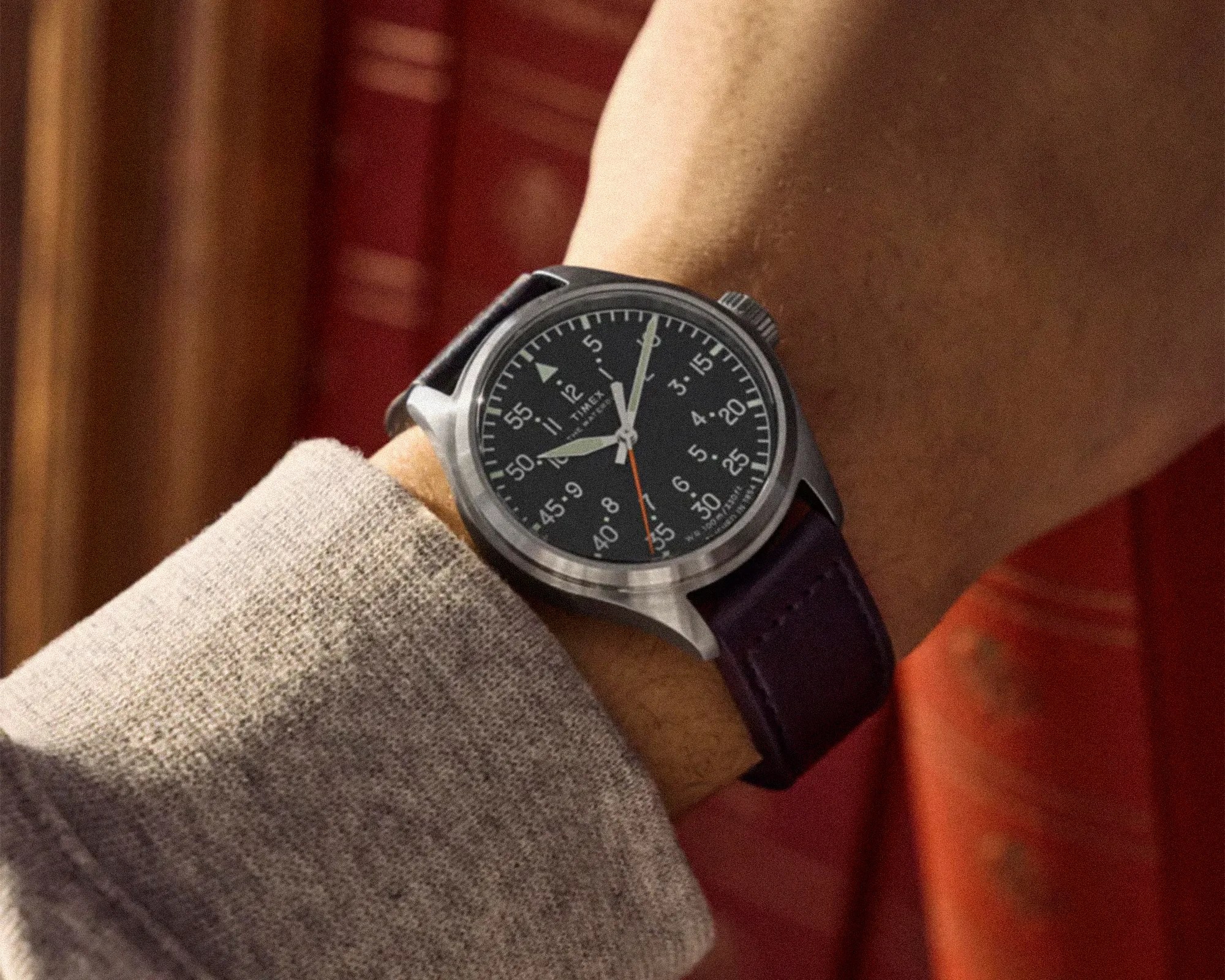 Wristwatch with black dial, white numerals, silver case, and dark leather strap worn on a wrist.