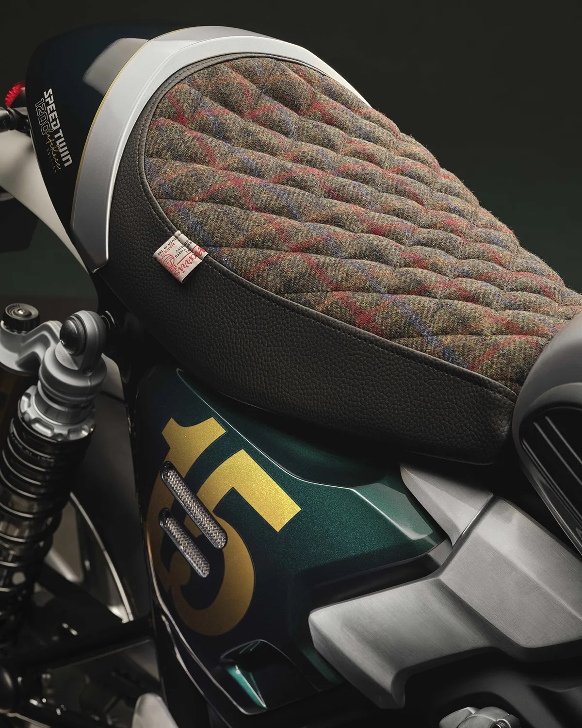 Quilted tweed motorcycle seat with black leather trim on a green bike with gold number 15 decal.