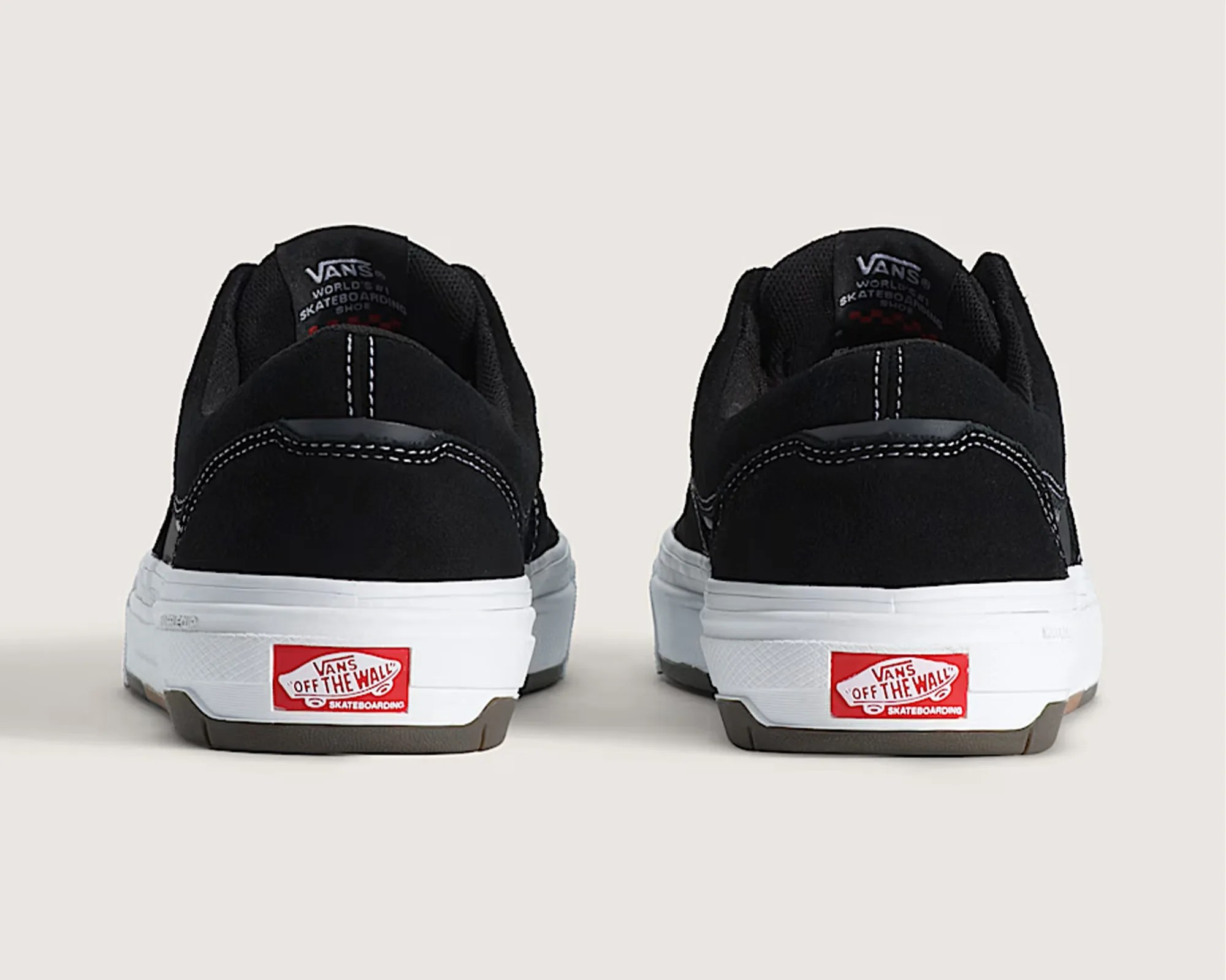 Pair of black Vans skateboarding shoes with white midsoles and red "Off The Wall" logos on the heels.