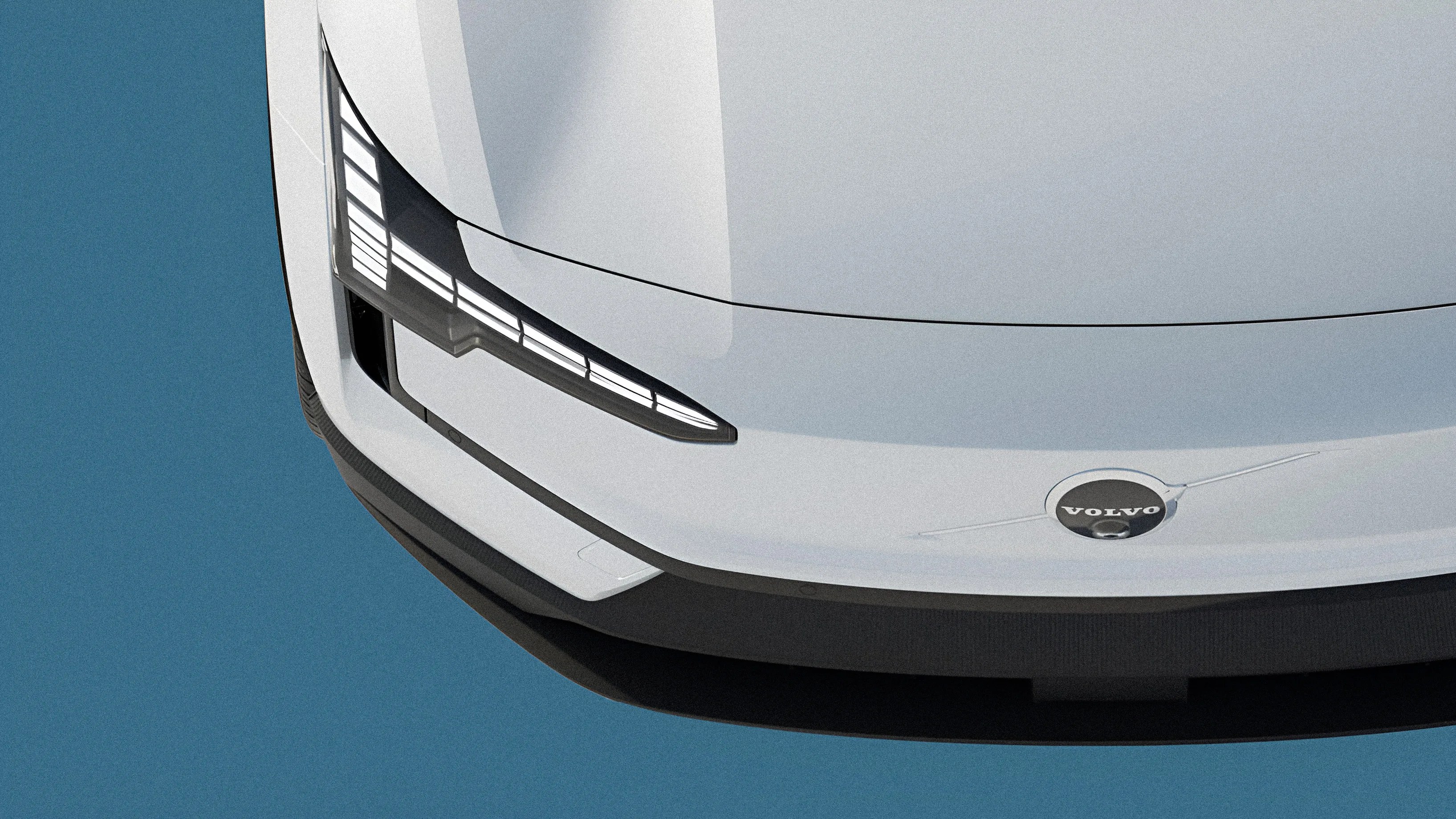 Close-up of the front left corner of a white Volvo car showing the headlight and logo on a blue background.