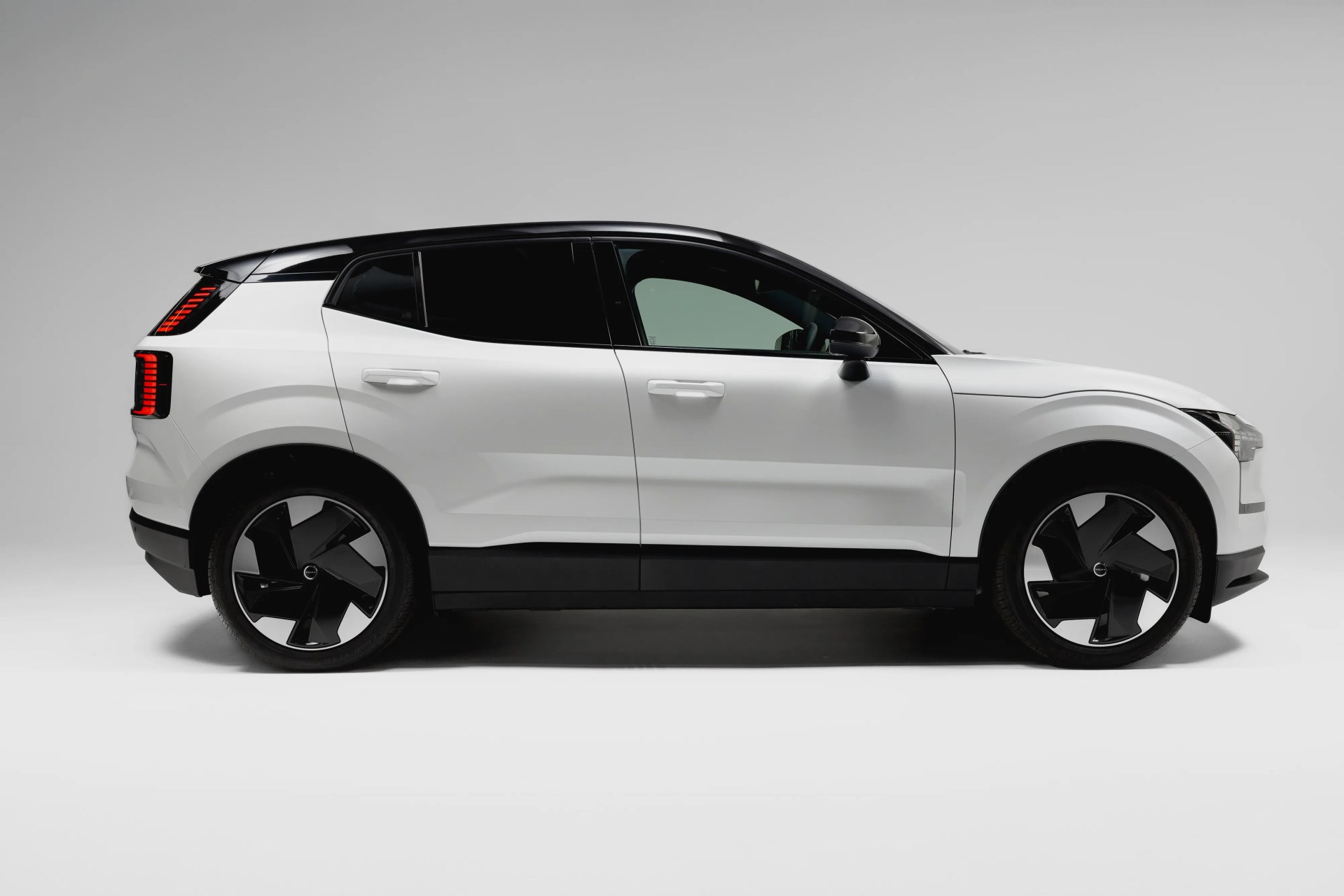 White compact SUV with black roof and large black alloy wheels on a plain gray background.