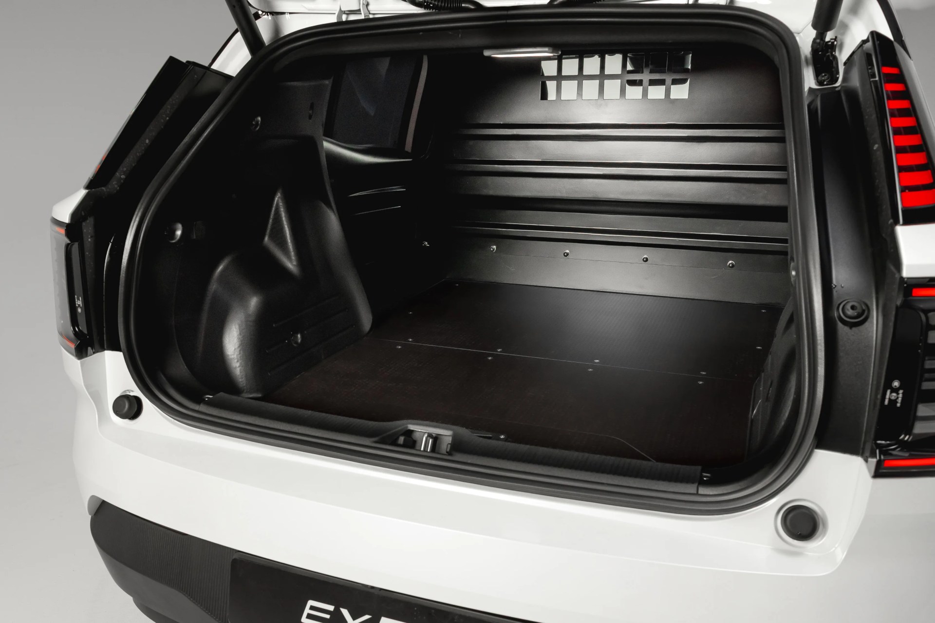 Empty black cargo area of a white vehicle with a flat floor and a partition wall.