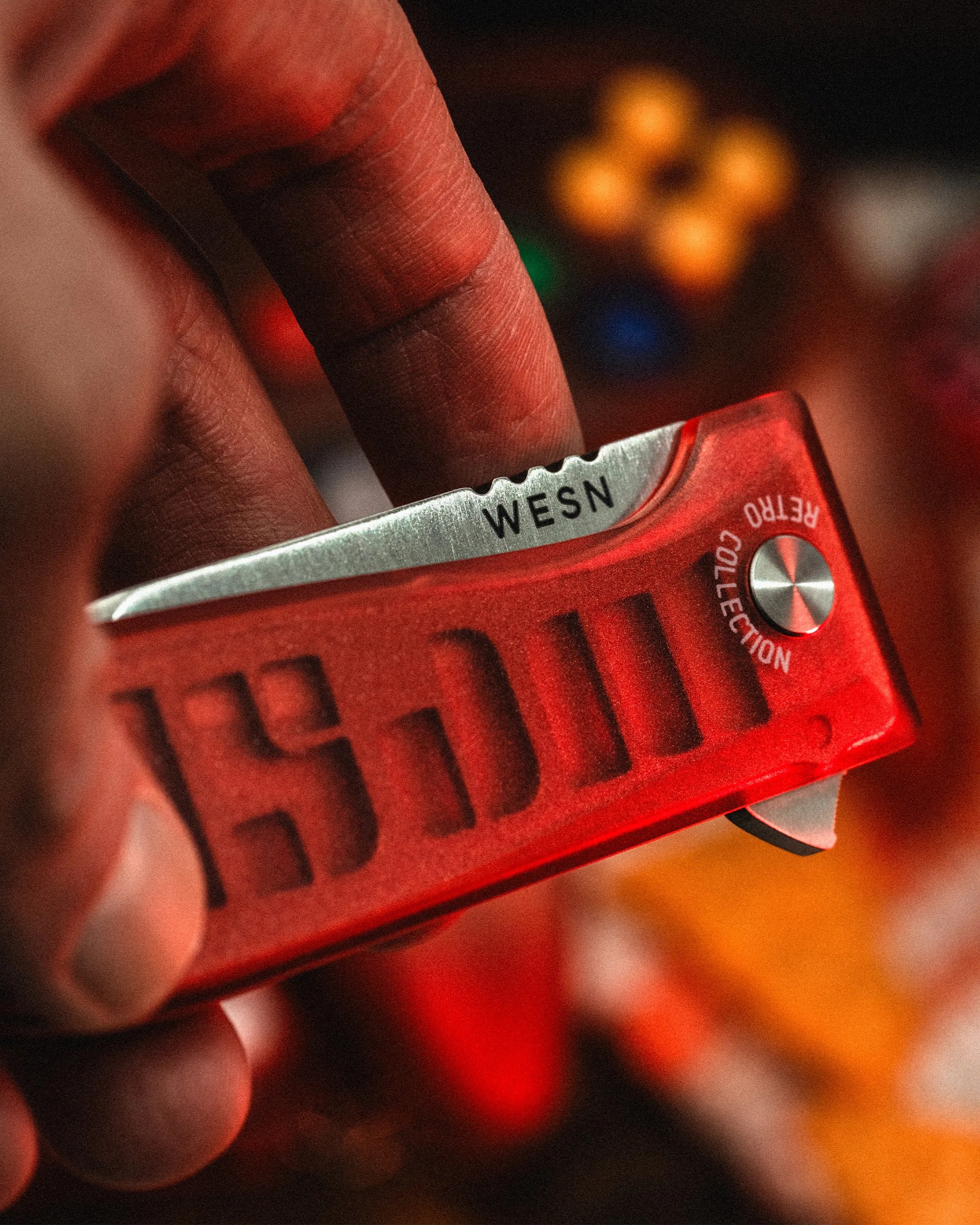 Hand holding a red translucent folding knife with "WESN" on the blade and "RETRO COLLECTION" on the handle.