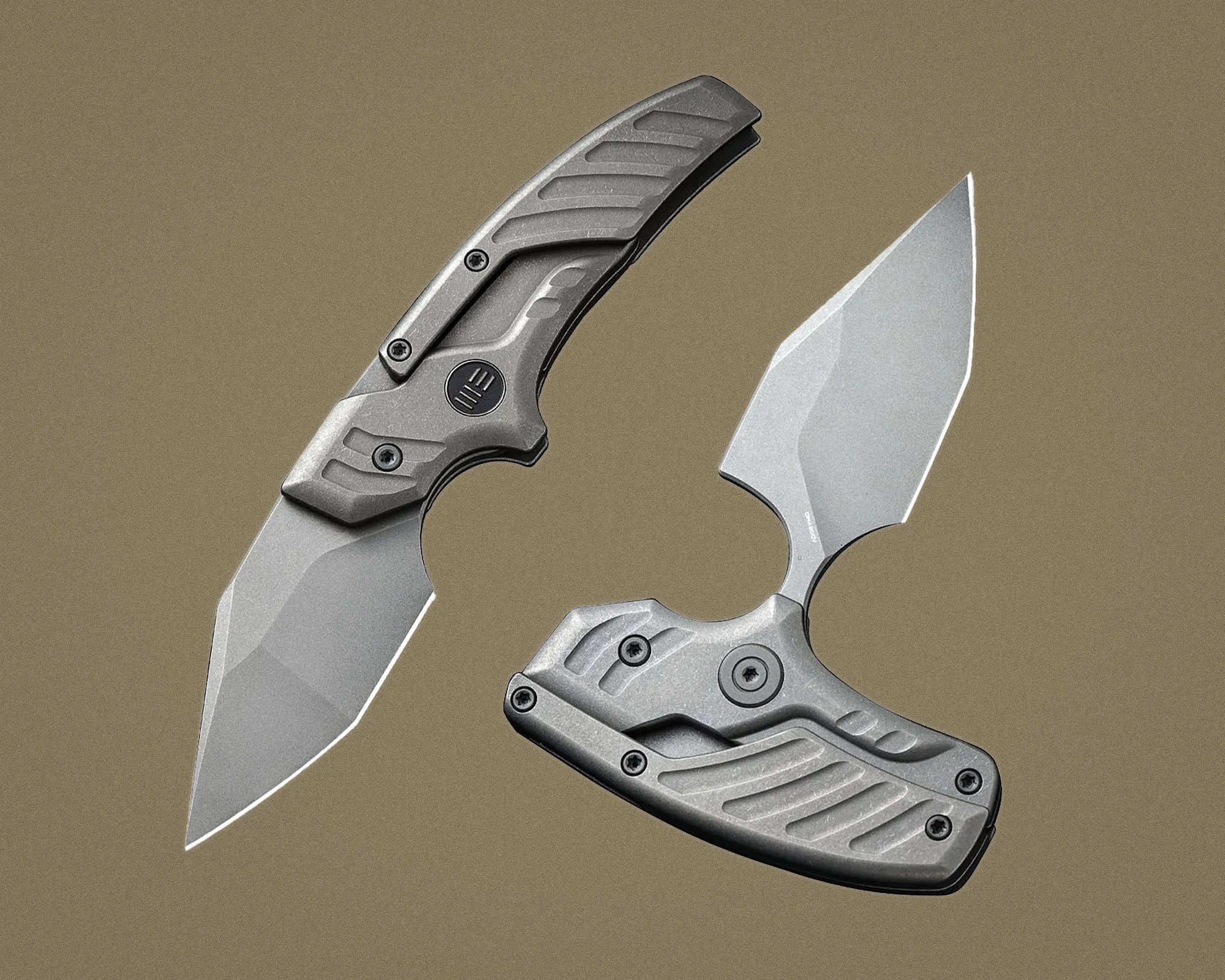 Two gray folding knives with textured handles and angular blades on a brown background.