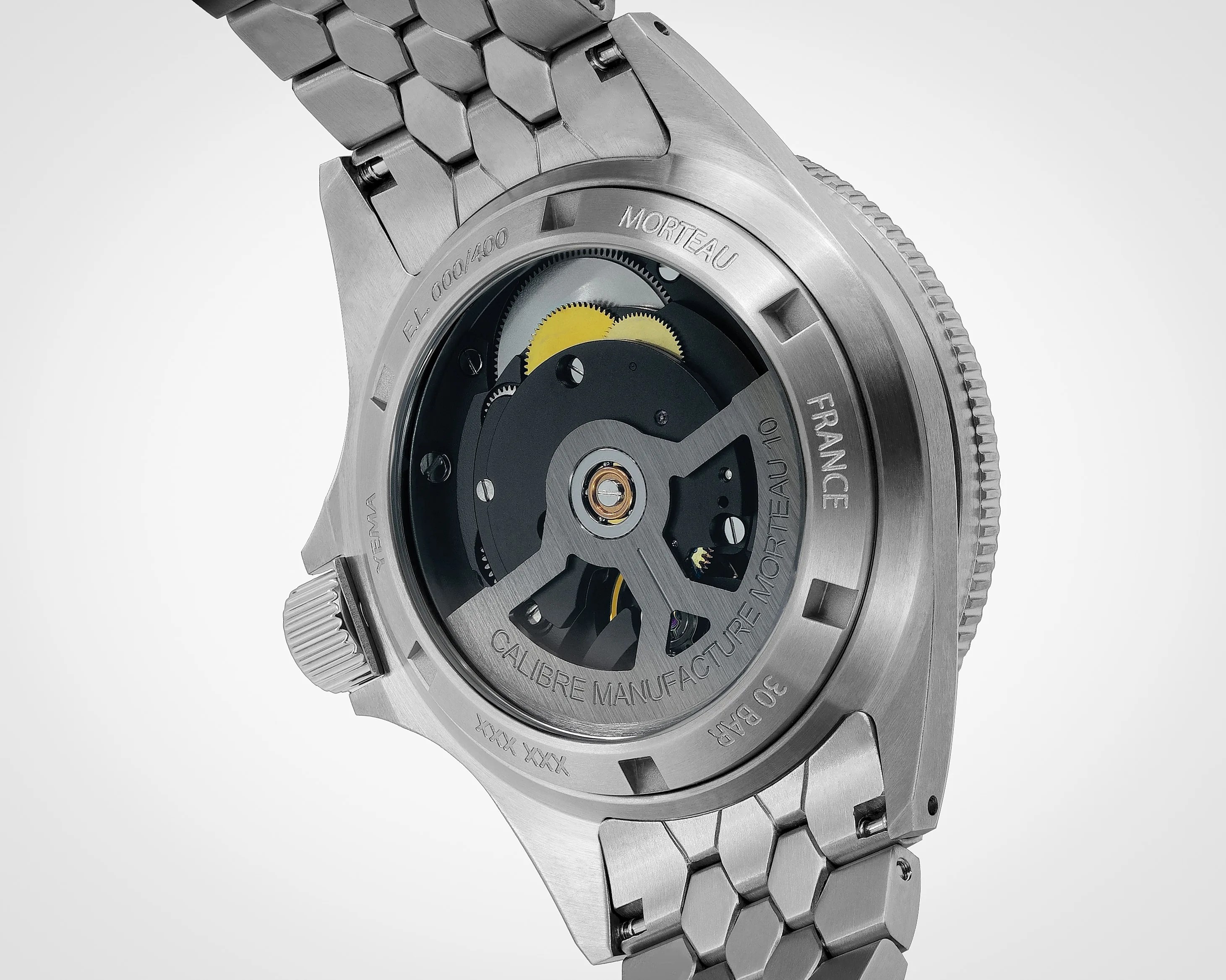 Back of a stainless steel wristwatch showing the mechanical movement with visible gears and engraved text on the case back.