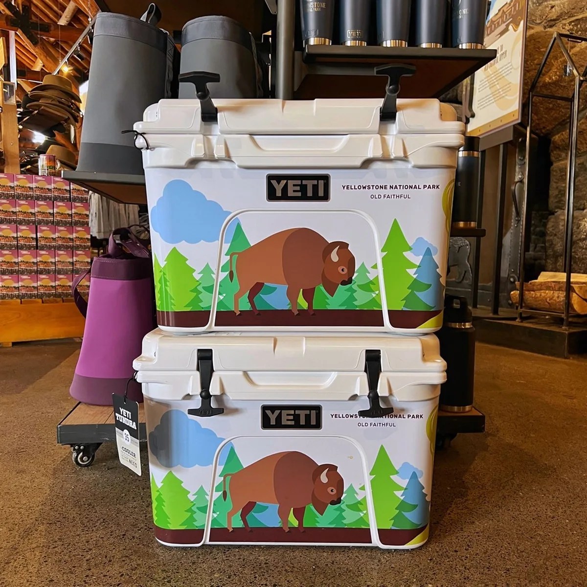 Two stacked white YETI coolers with Yellowstone National Park Old Faithful bison design on a store floor.