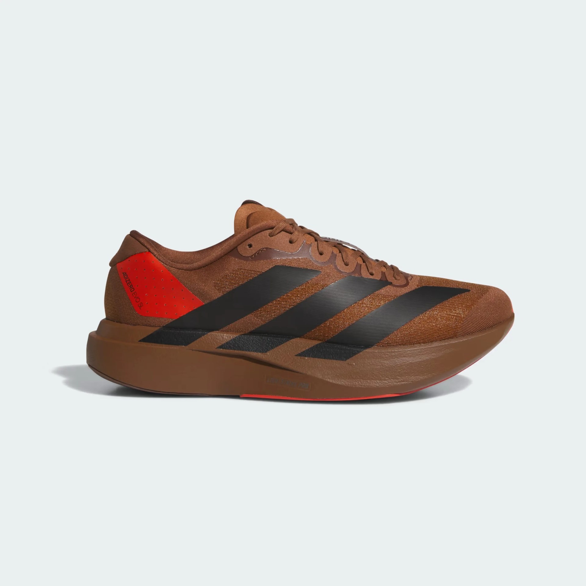 Brown Adidas running shoe with black stripes and red heel accent, side view.