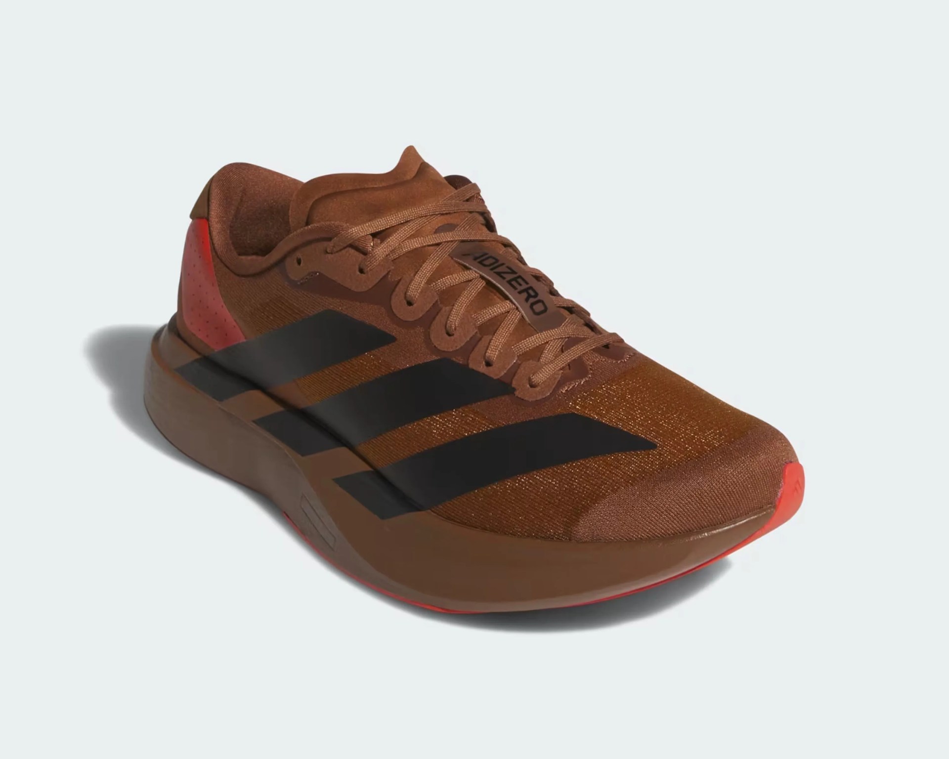 Brown Adidas running shoe with black stripes and red accents on the heel and sole.