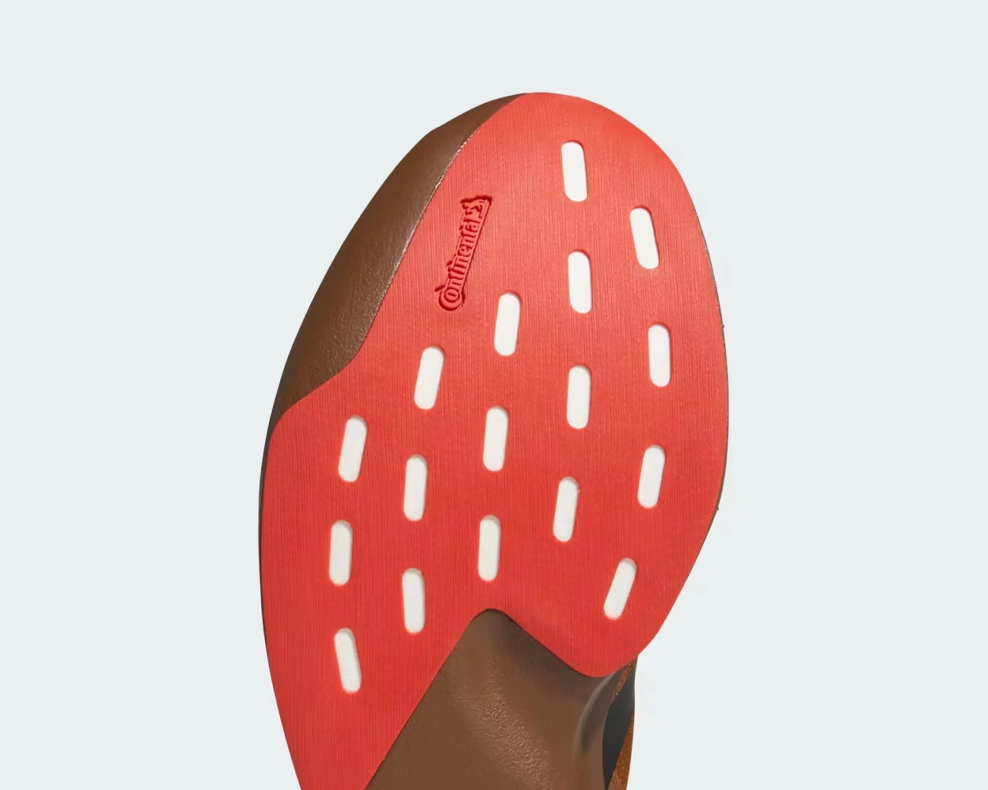 Close-up of a brown shoe sole with a red rubber section featuring white rectangular cutouts and the Continental logo.