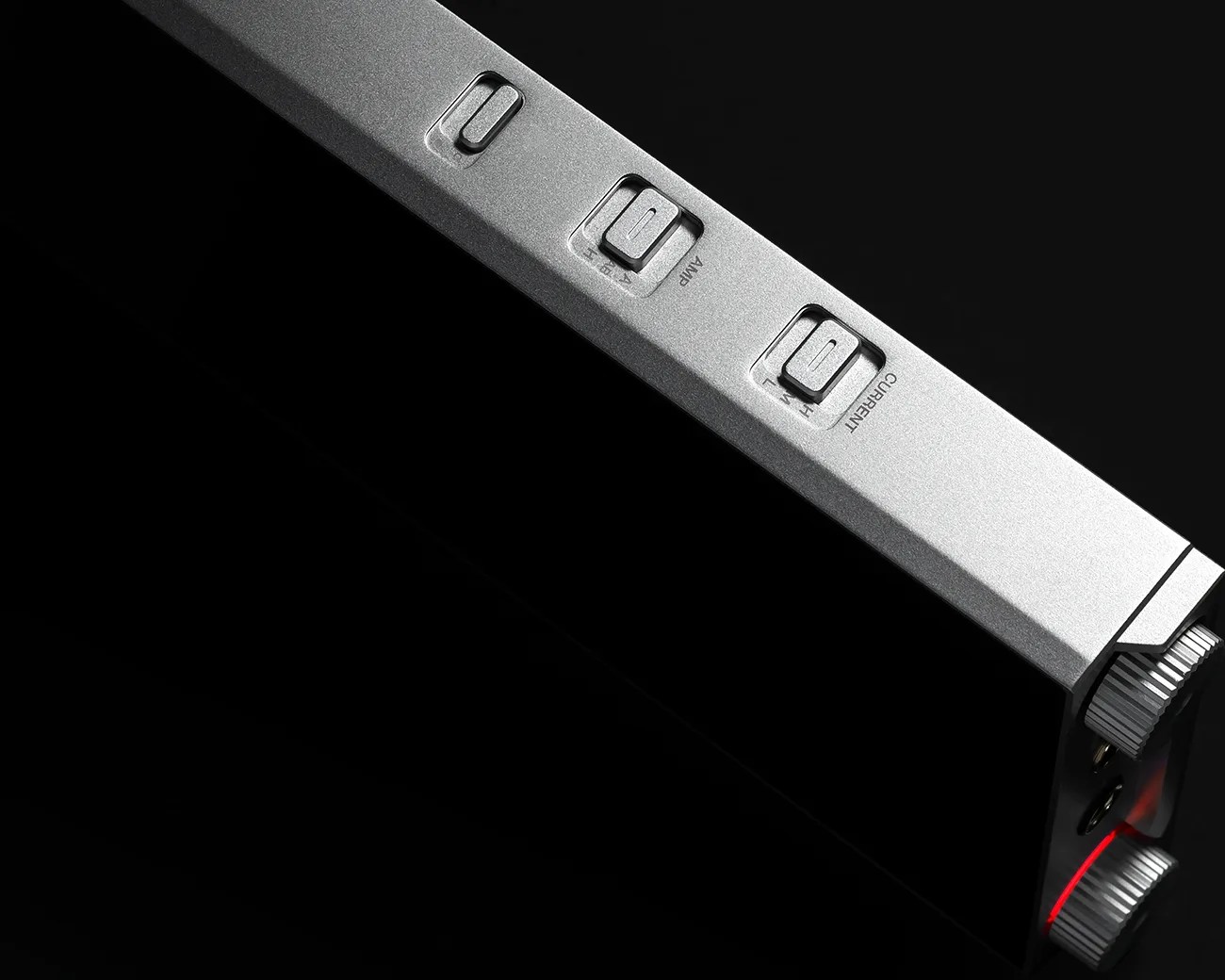 Silver rectangular electronic device with three labeled switches and two knurled knobs on a black background.