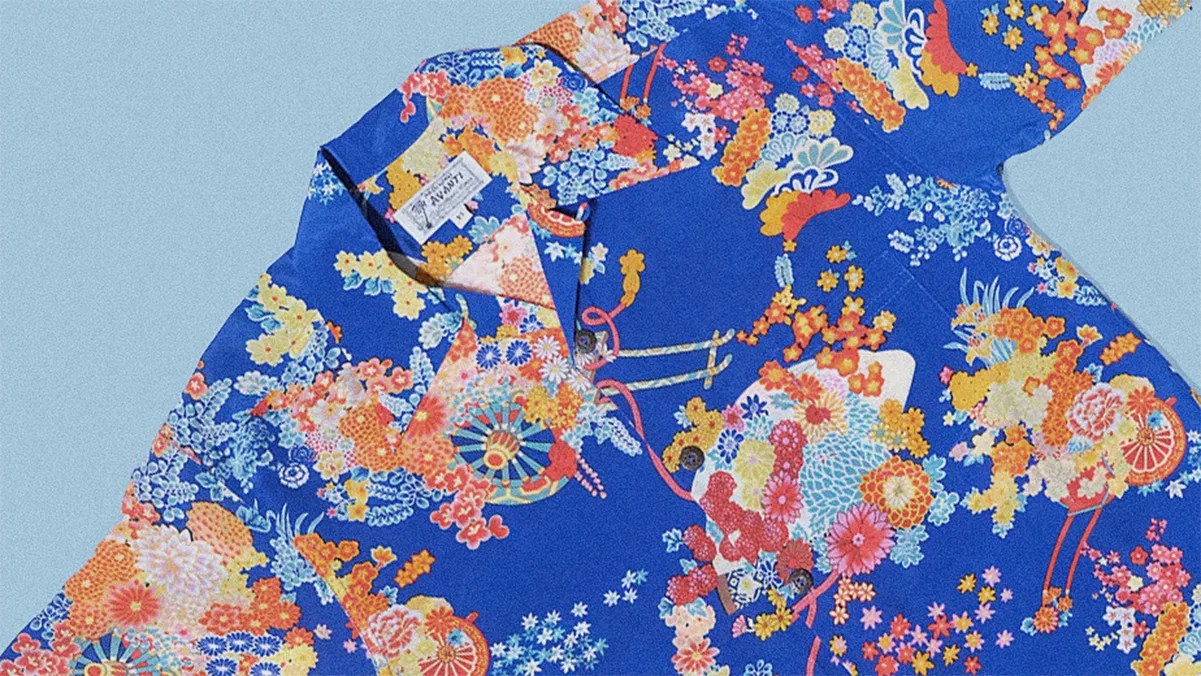 Blue short-sleeve shirt with vibrant multicolored floral and fan patterns.