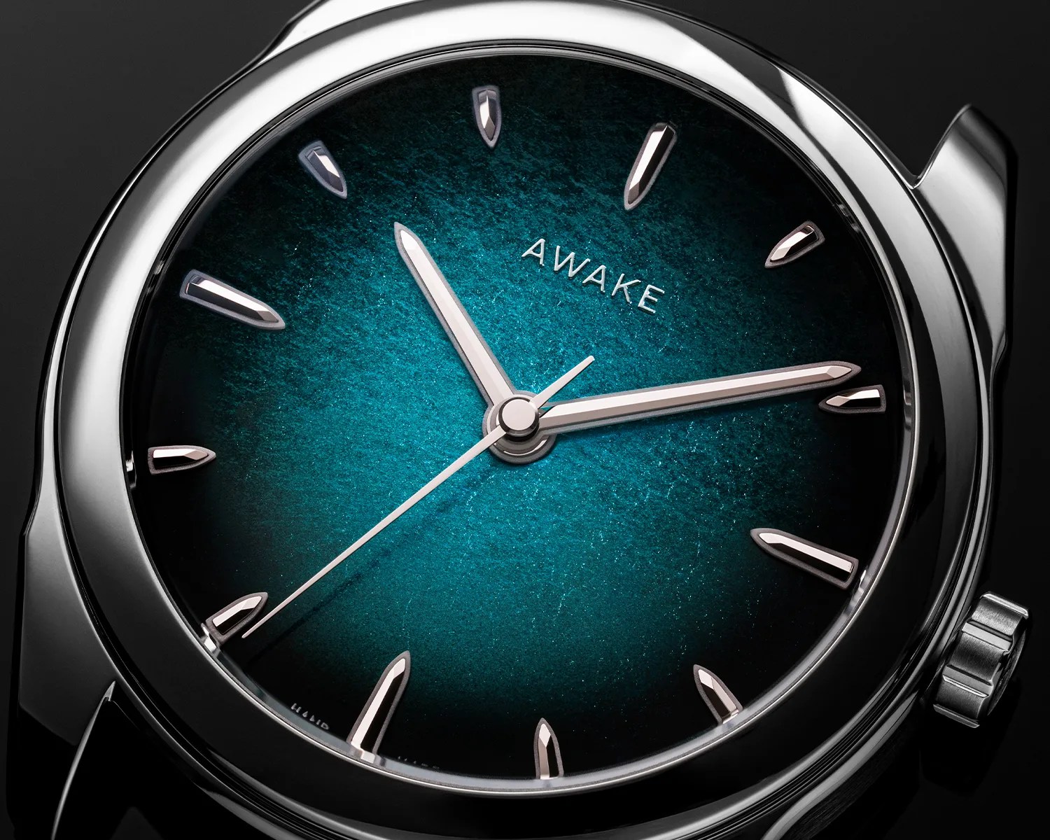 Close-up of a silver wristwatch with a textured blue-green dial and silver hour markers and hands.