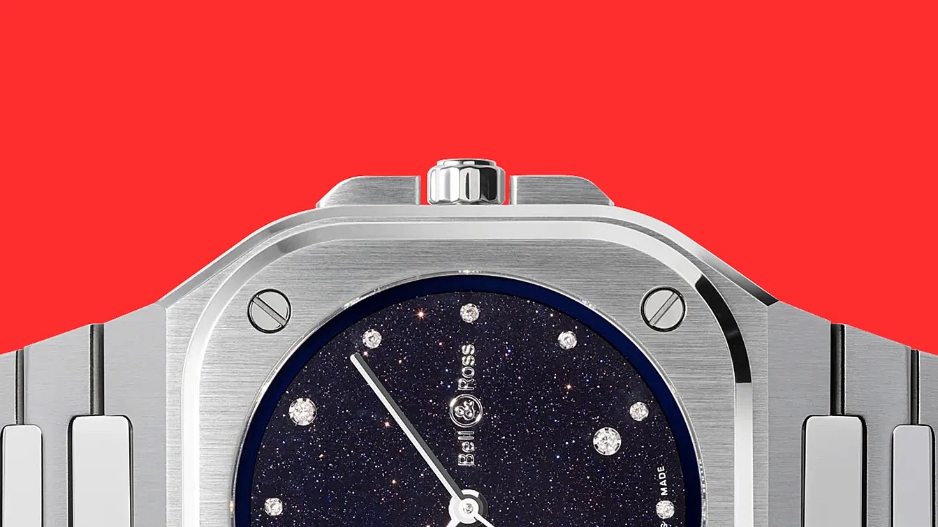 Close-up of a silver Bell & Ross watch with a starry black dial and diamond hour markers on a red background.