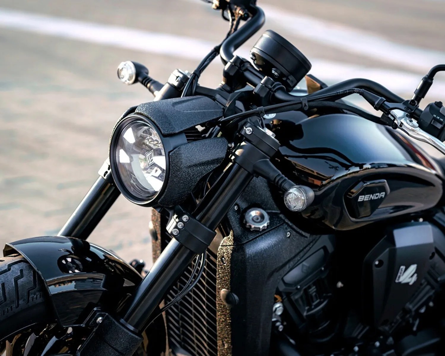 Close-up of a black Benda motorcycle headlight and front fork with a glossy fuel tank and turn signals.