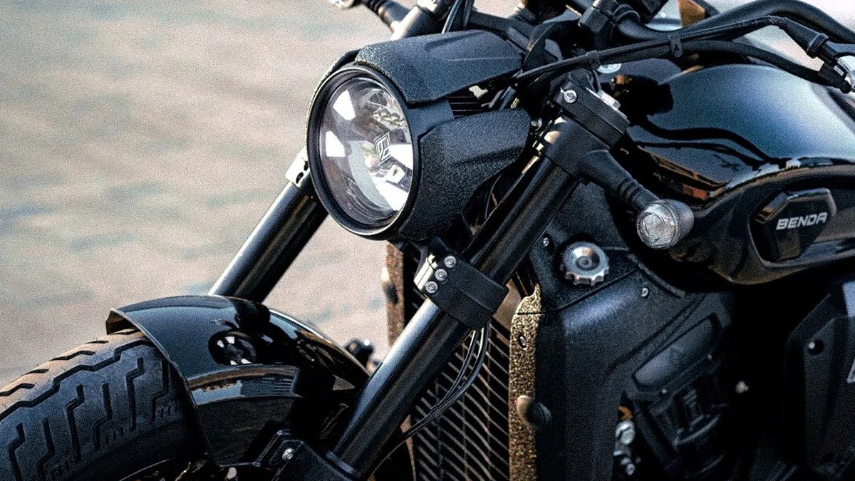 Close-up of a black Benda motorcycle front with round headlight, front tire, and handlebars.