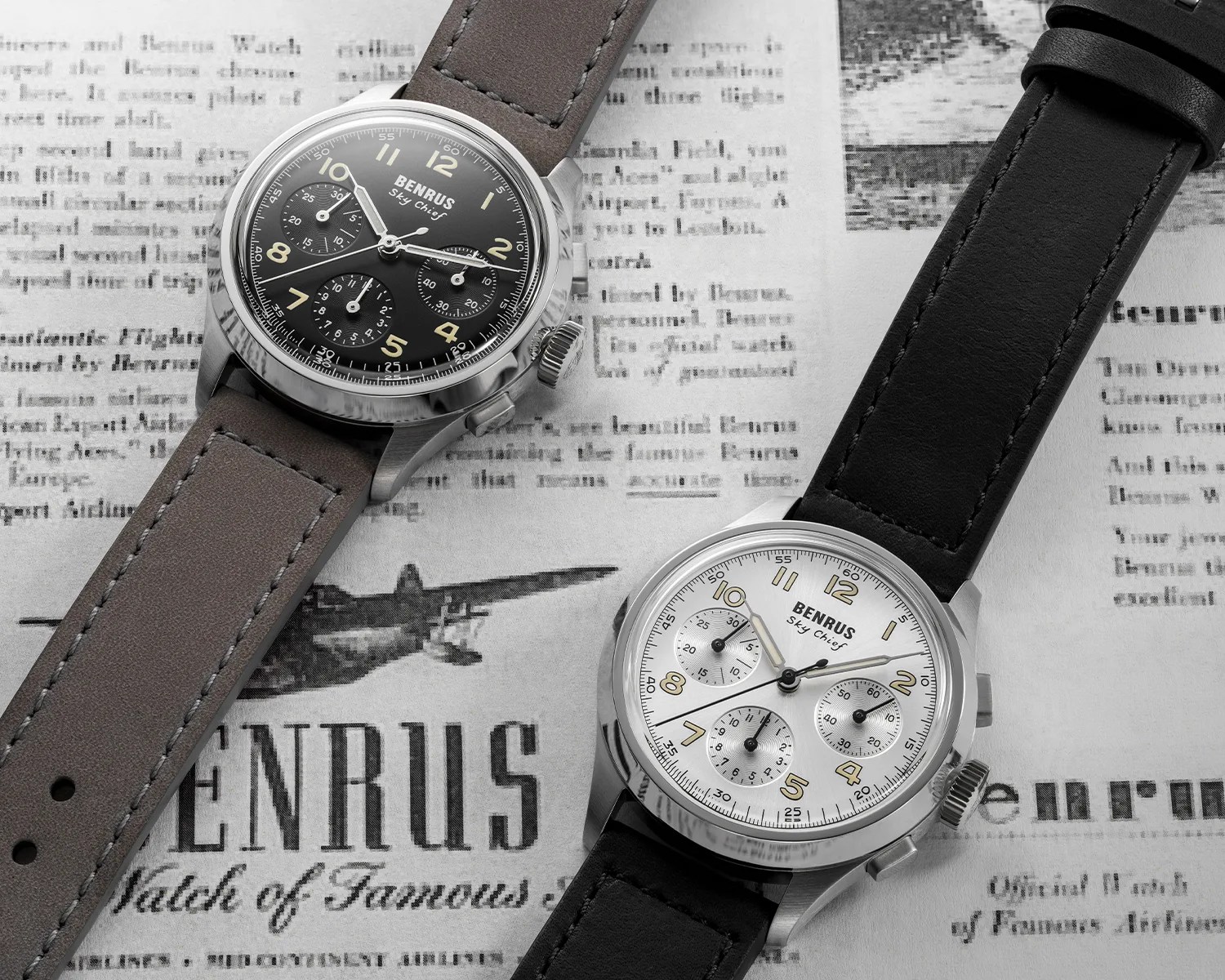 Two Benrus Sky Chief chronograph watches, one with a black dial and brown leather strap, the other with a white dial and black leather strap, placed on a vintage newspaper background.