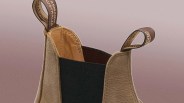 Close-up of the top part of a tan leather boot with black elastic side panels and brown pull tabs with text.