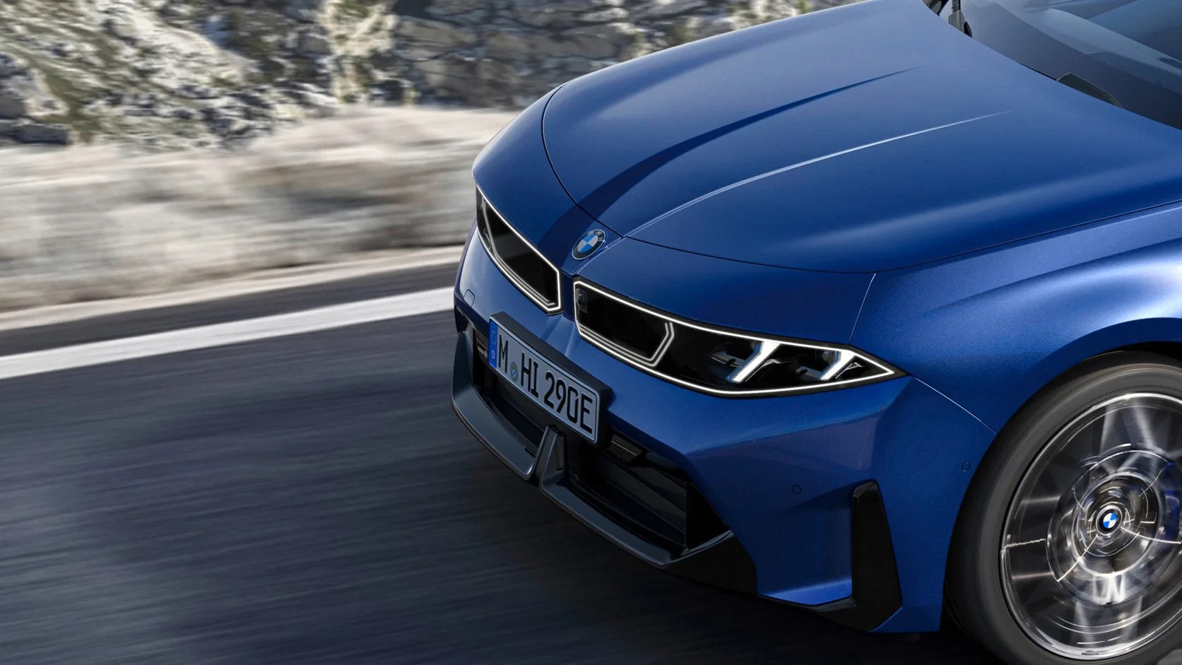 Front view of a blue BMW car with illuminated headlights and spinning front wheel on a road.
