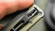 Close-up of a hand holding an olive green and black folding knife with a pocket clip.