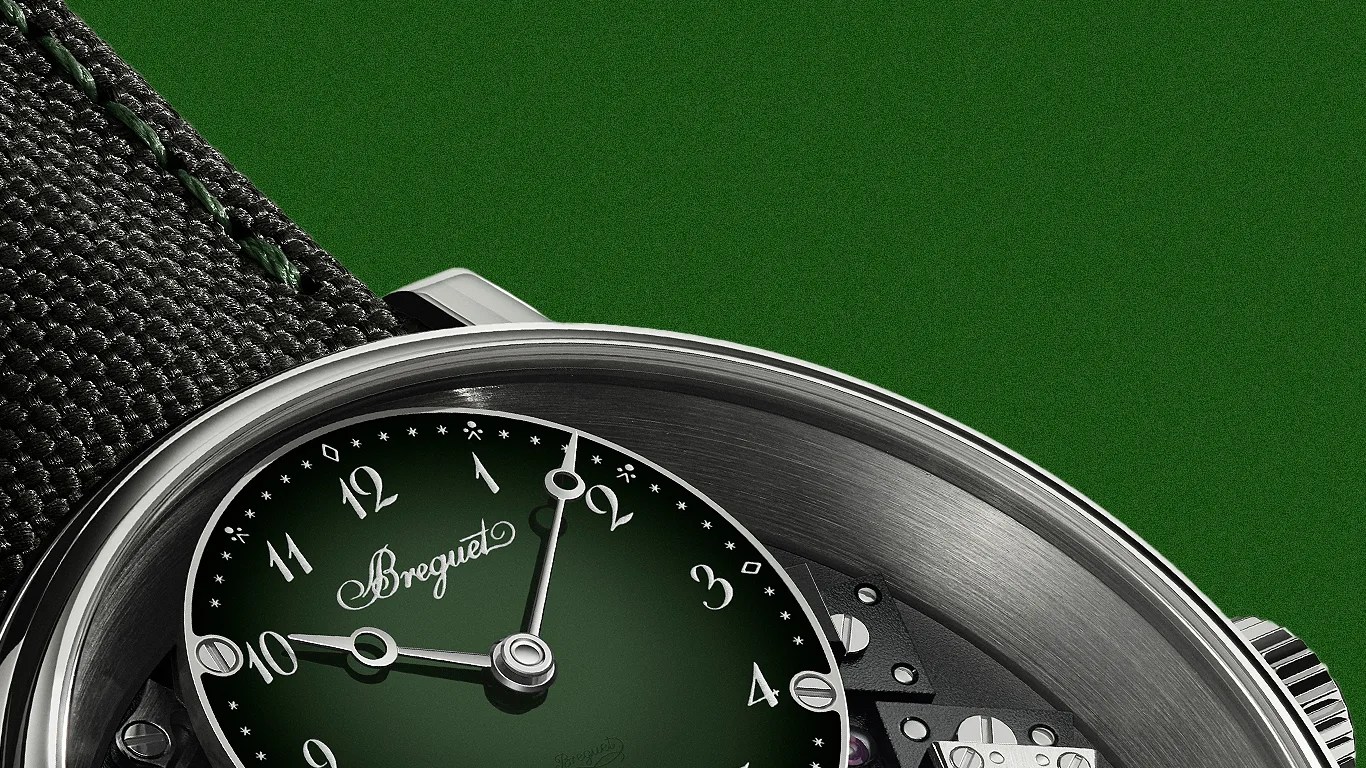 Close-up of a Breguet watch with a green dial, silver hands, and a black textured strap against a green background.