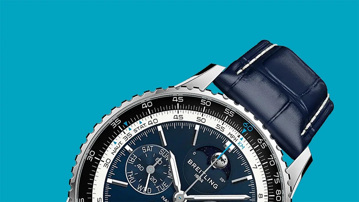 Close-up of a Breitling watch with a blue dial, moon phase indicator, and blue leather strap against a teal background.
