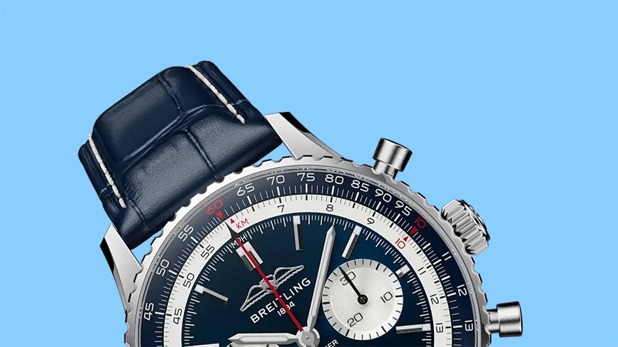 Close-up of a Breitling watch with a blue dial, silver subdial, and dark blue leather strap against a blue background.