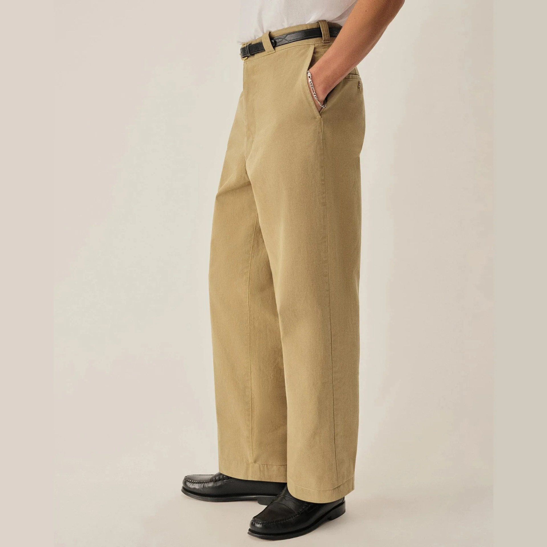 Wide-leg beige pants with side pockets worn with a black belt and black loafers.