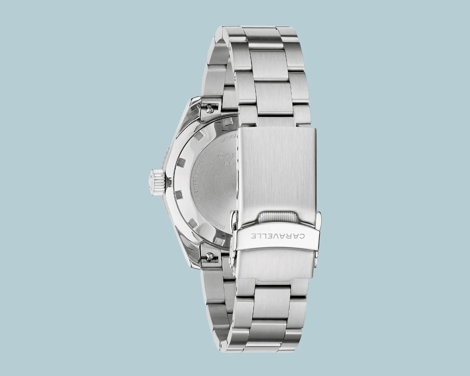 Silver stainless steel watch bracelet with a clasp engraved "CARAVELLE" against a light blue background.