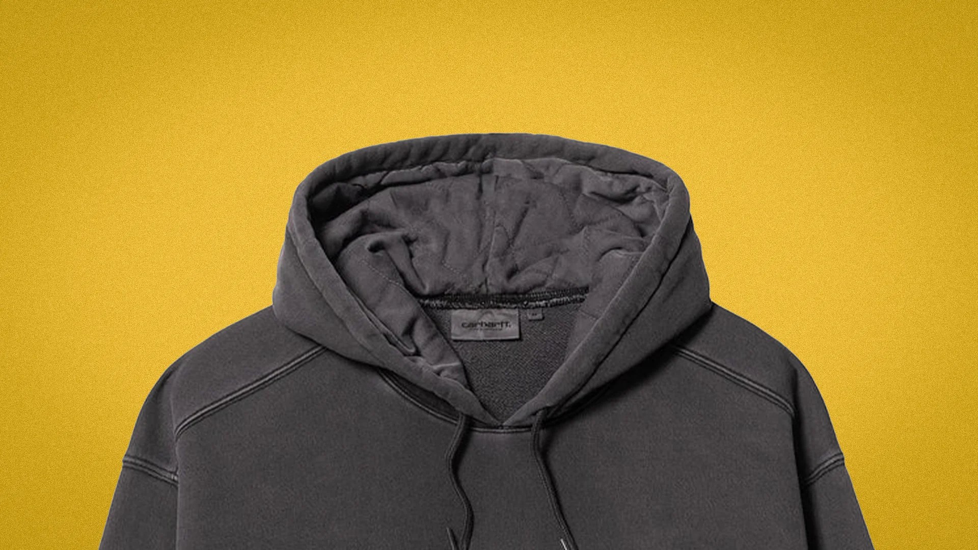 Dark gray Carhartt hooded sweatshirt with visible stitching on a yellow background.