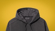 Dark gray Carhartt hooded sweatshirt with visible stitching on a yellow background.