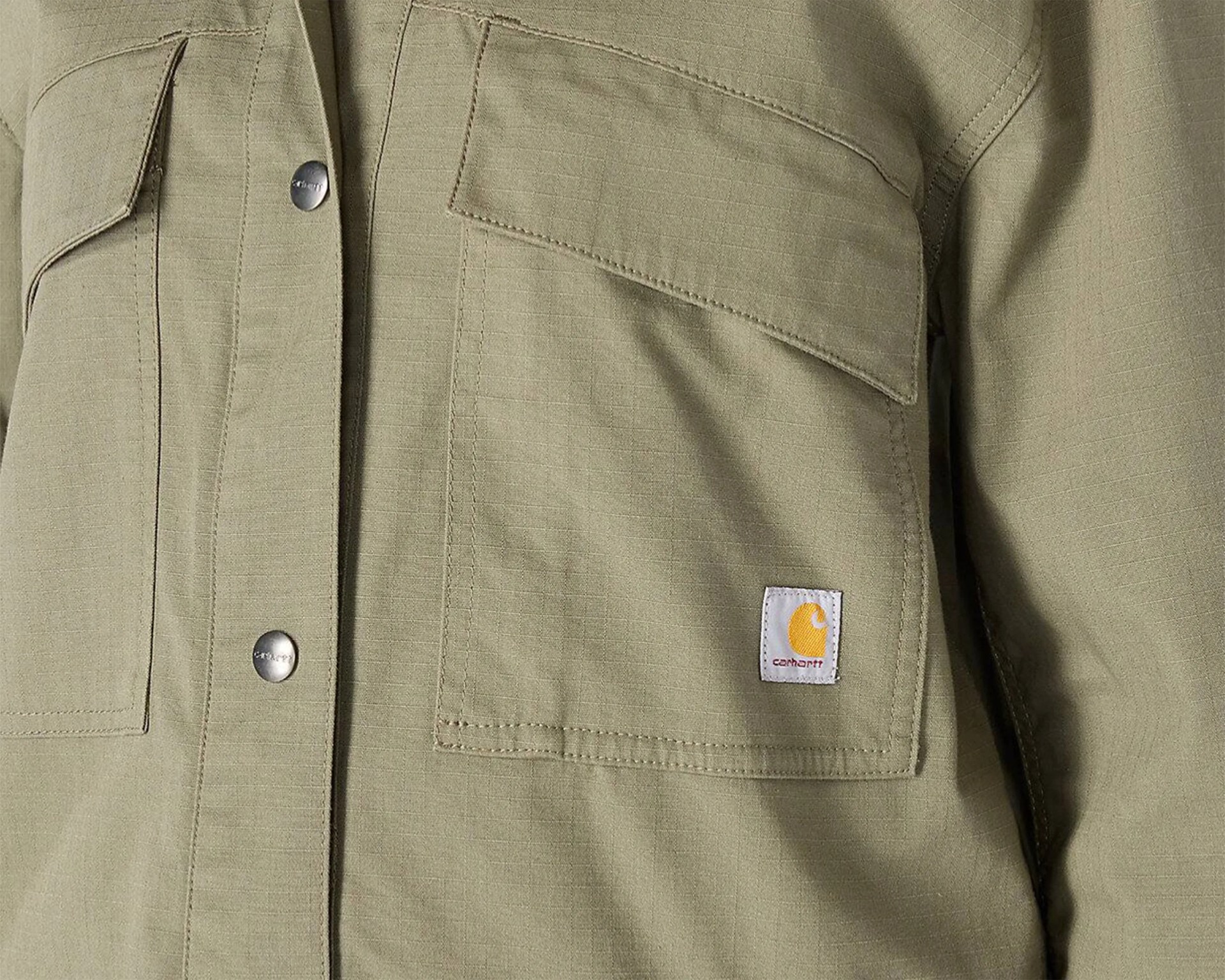 Close-up of olive green Carhartt jacket with flap pockets and metal snap buttons.